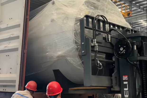 The wrapped WNS boiler is lifted into the container by forklift.